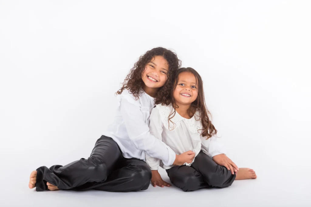 Twee lachende meisjes samen op de foto tegen een witte achtergrond