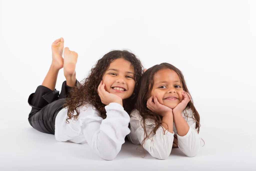 Twee meisjes liggen op hun buik met hun kin in hun handen