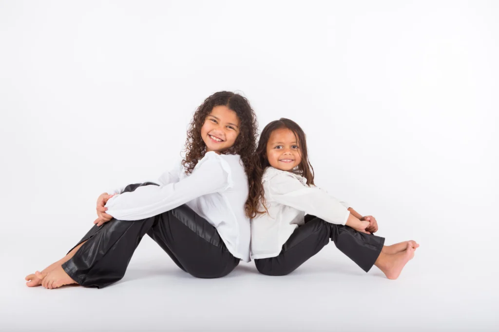 Twee meisjes zitten rug aan rug op de studiovloer