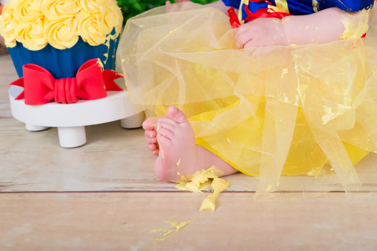 Meisje in Sneeuwwitje-jurkje bij haar cakesmash taart met rode strik, fotostudio Zoetermeer