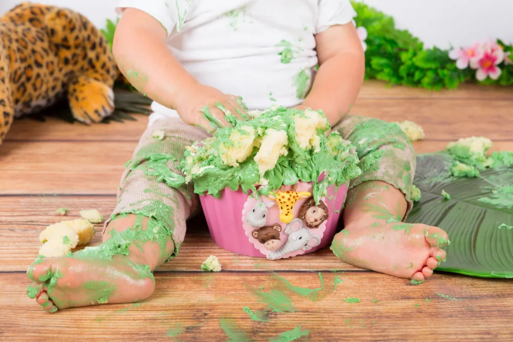 Kindje kliedert met de groene jungle cake smash taart op de houten vloer, cakesmash fotoshoot Zoetermeer