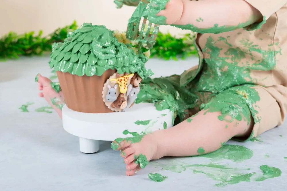 Kindje in beige pakje onder de groene slagroom van de safari cake smash taart, cakesmash fotoshoot Zoetermeer