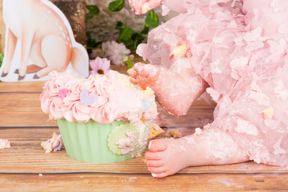 Kindje in roze tulejurk met vlinders kliedert met de sprookjesbos cake smash taart op de houten vloer, cakesmash fotoshoot Zoetermeer
