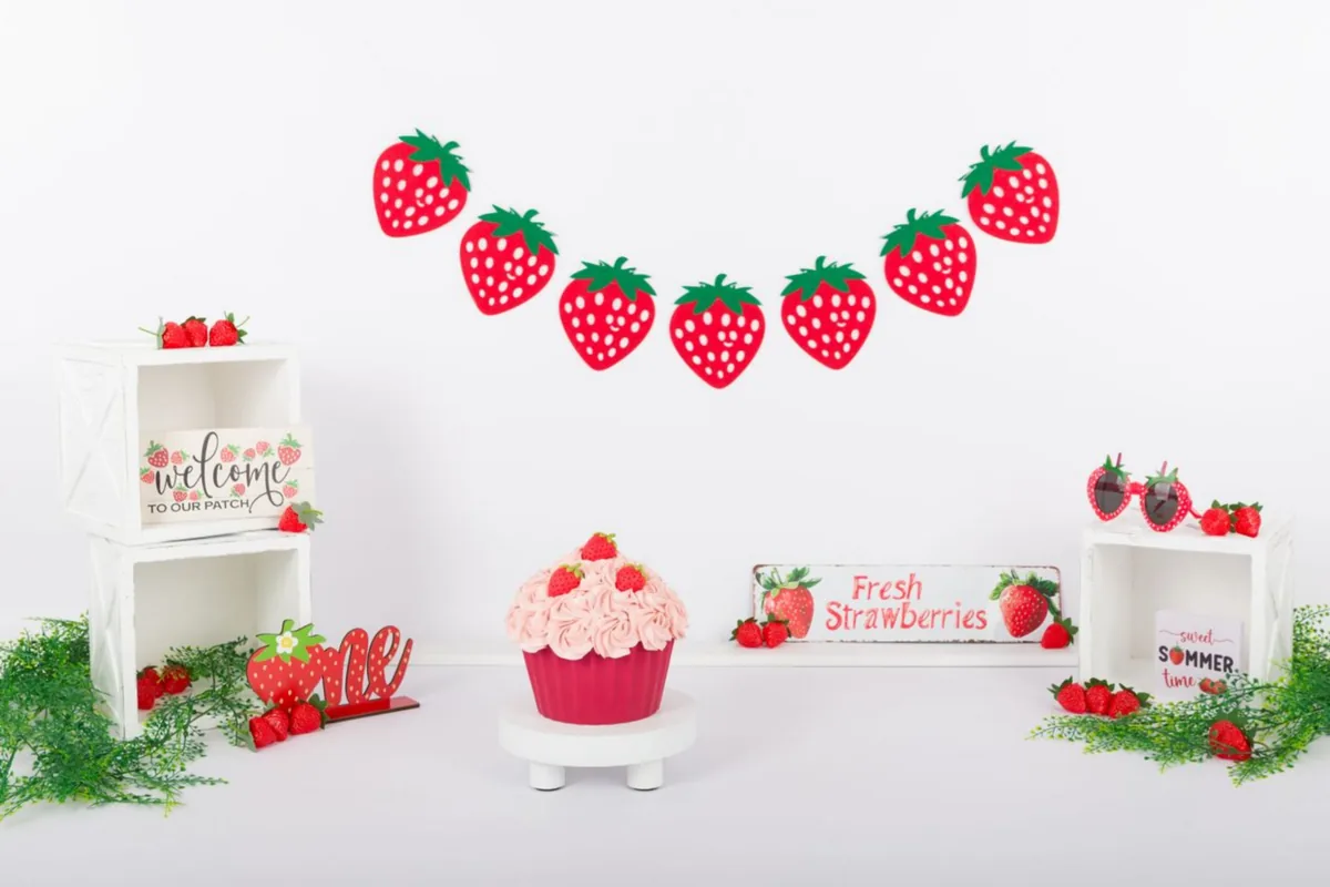 Aardbeien cake smash decor met aardbeienslinger, kratjes en een roze taart, cakesmash fotoshoot Zoetermeer