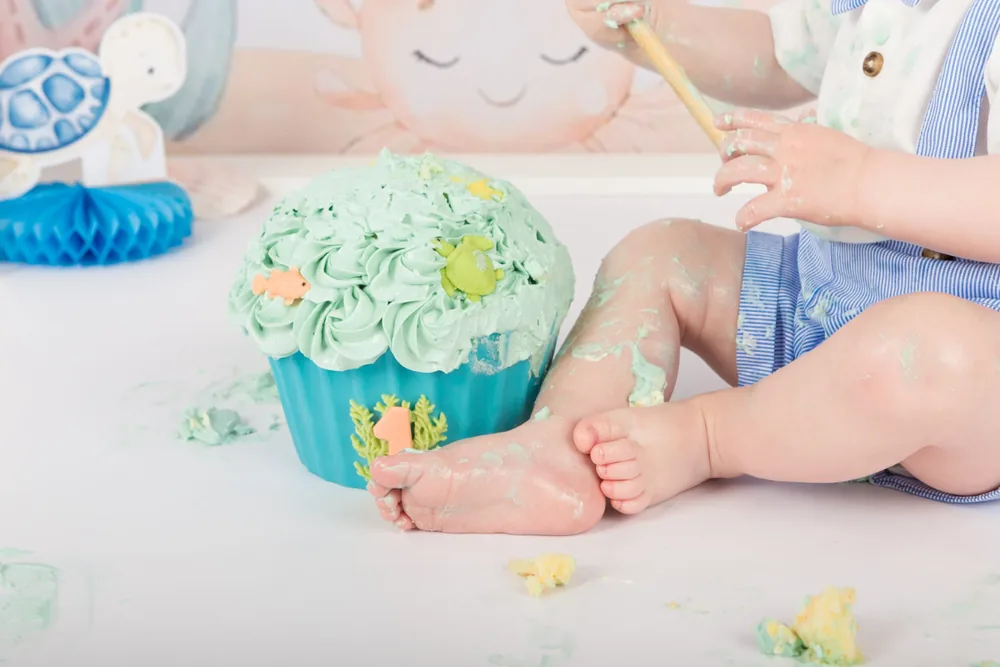 Kindje in blauw gestreepte tuinbroek kliedert met de mintgroene zeetaart, cakesmash fotoshoot Zoetermeer