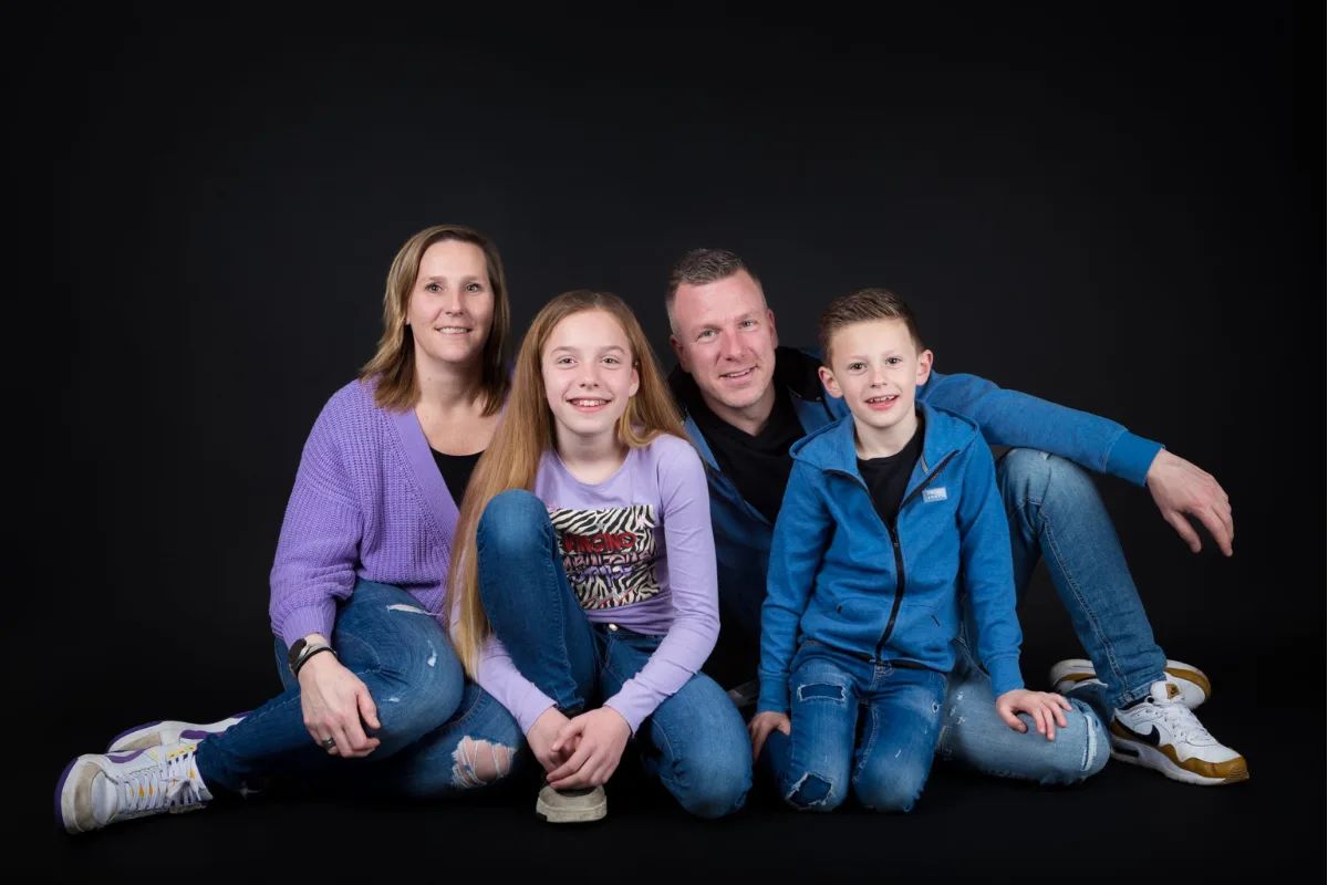 Gezin van vier zit samen op de vloer tijdens een familie fotoshoot
