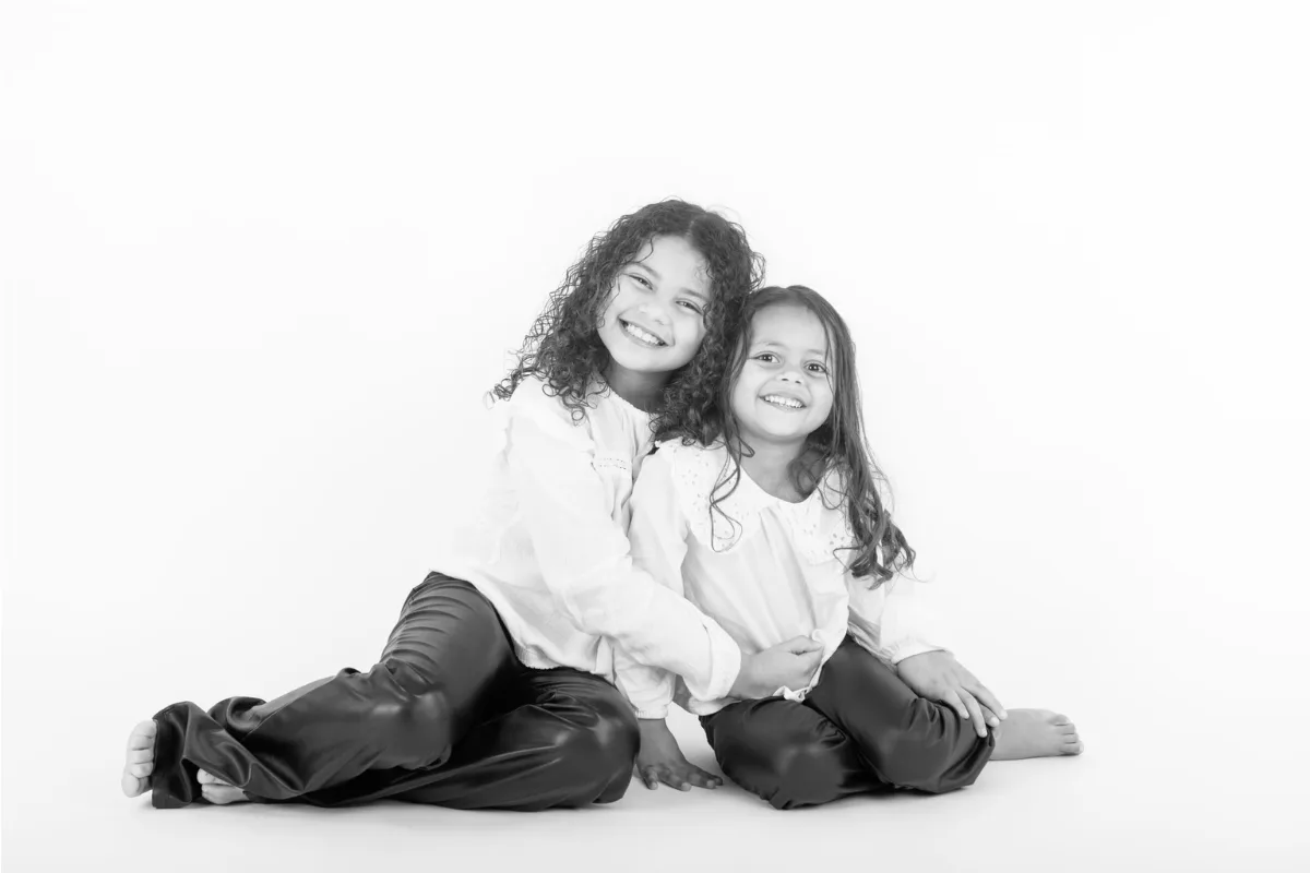 Zwart-witfoto van twee meisjes die samen op de studiovloer zitten
