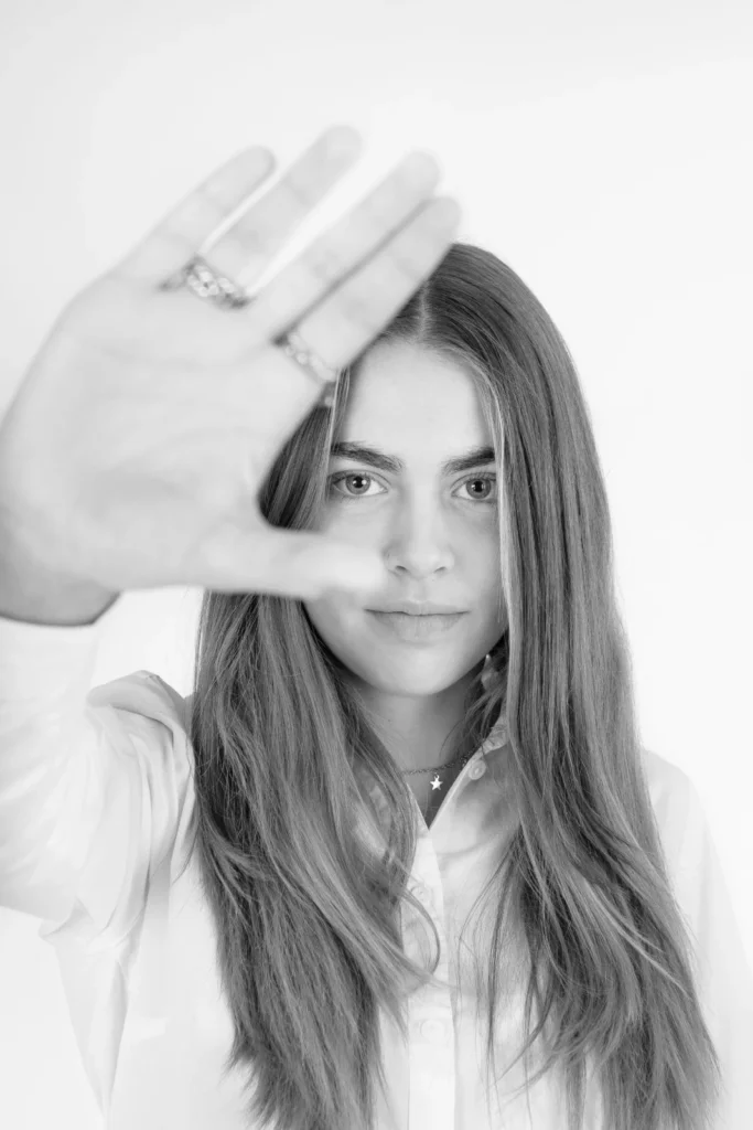 Zwart-witportret van een tienermeisje met haar hand voor de camera