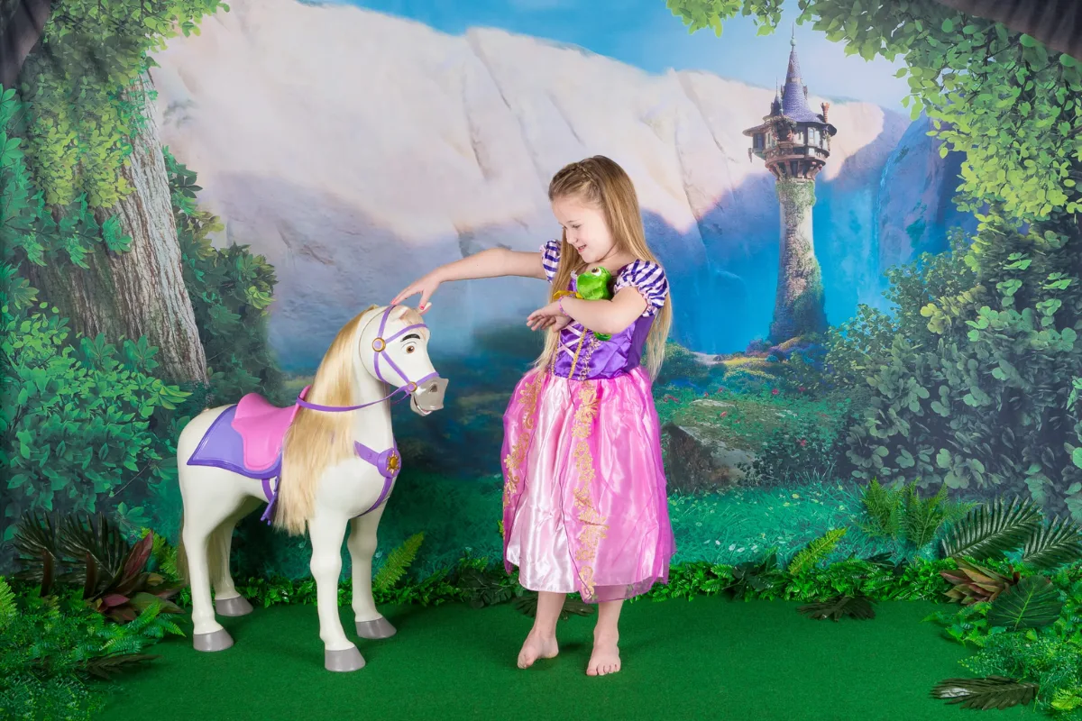 Meisje verkleed als Rapunzel in een sprookjesbos decor met paard