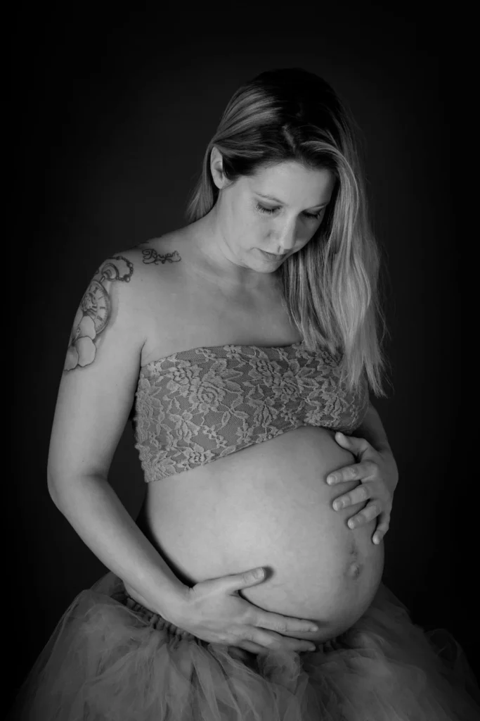 Zwangere vrouw met blote buik en kanten top, zwart-witfoto