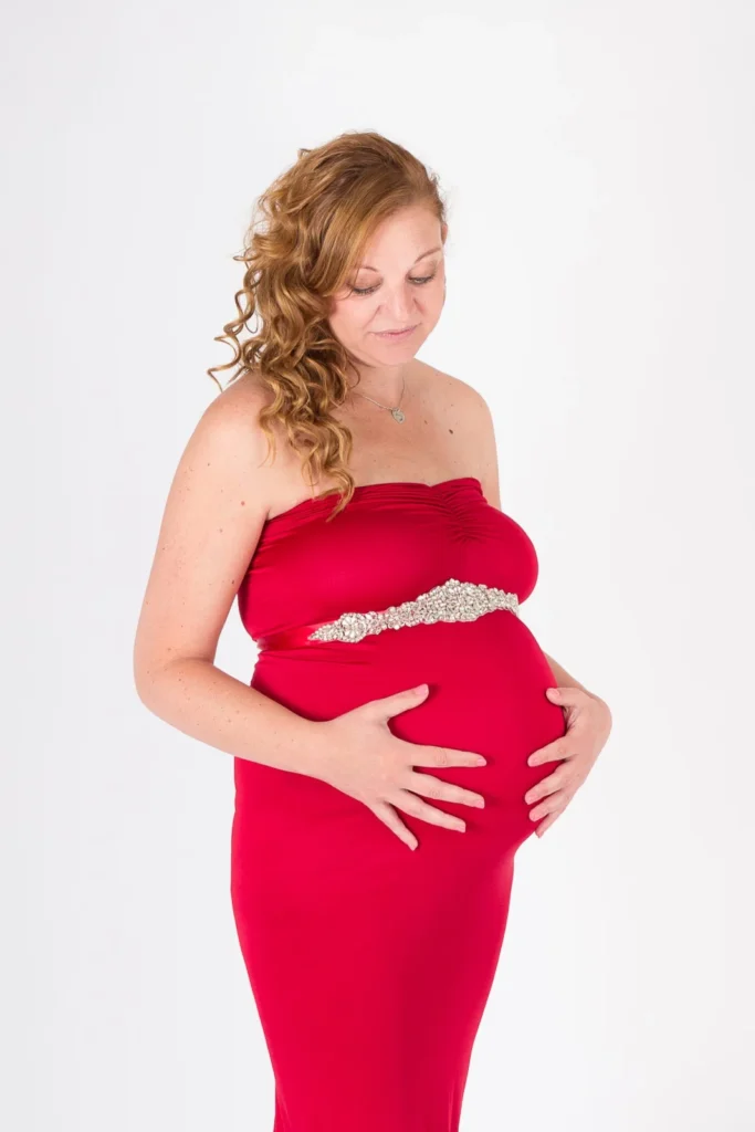Zwangere vrouw in een rode strapless zwangerschapsjurk