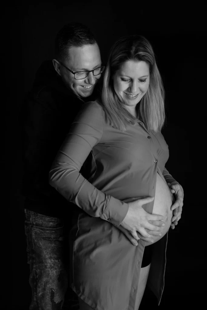 Zwart-wit zwangerschapsfoto van een aanstaande moeder met haar partner