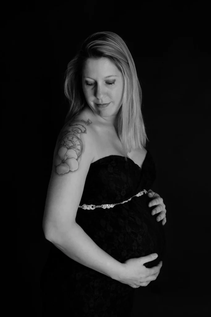 Zwangere vrouw in een zwarte kanten jurk, zwart-witfoto in de studio
